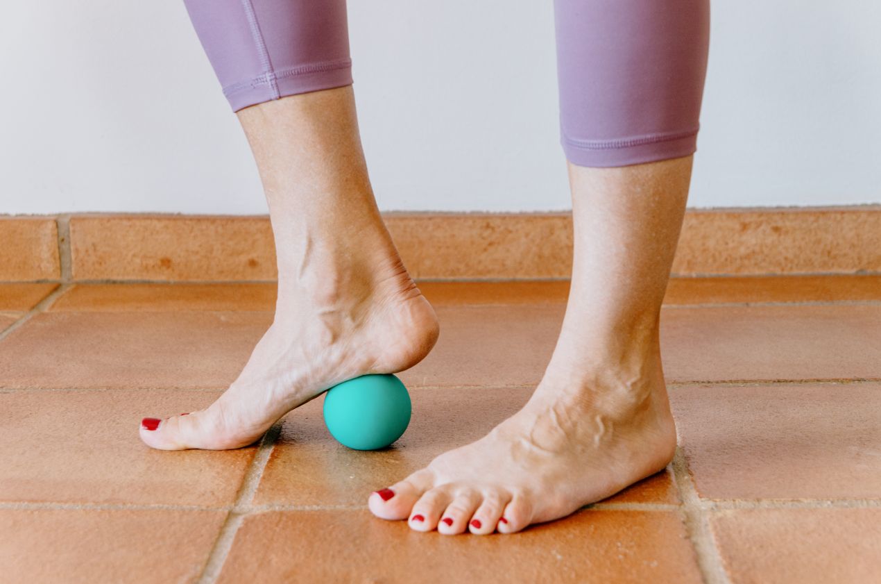 Ein Fuss rollt ueber einen Therapieball auf Fliesenboden – effektive Uebung zur Vorbereitung auf Barfussschuhe und gesunde Fussmuskulatur
