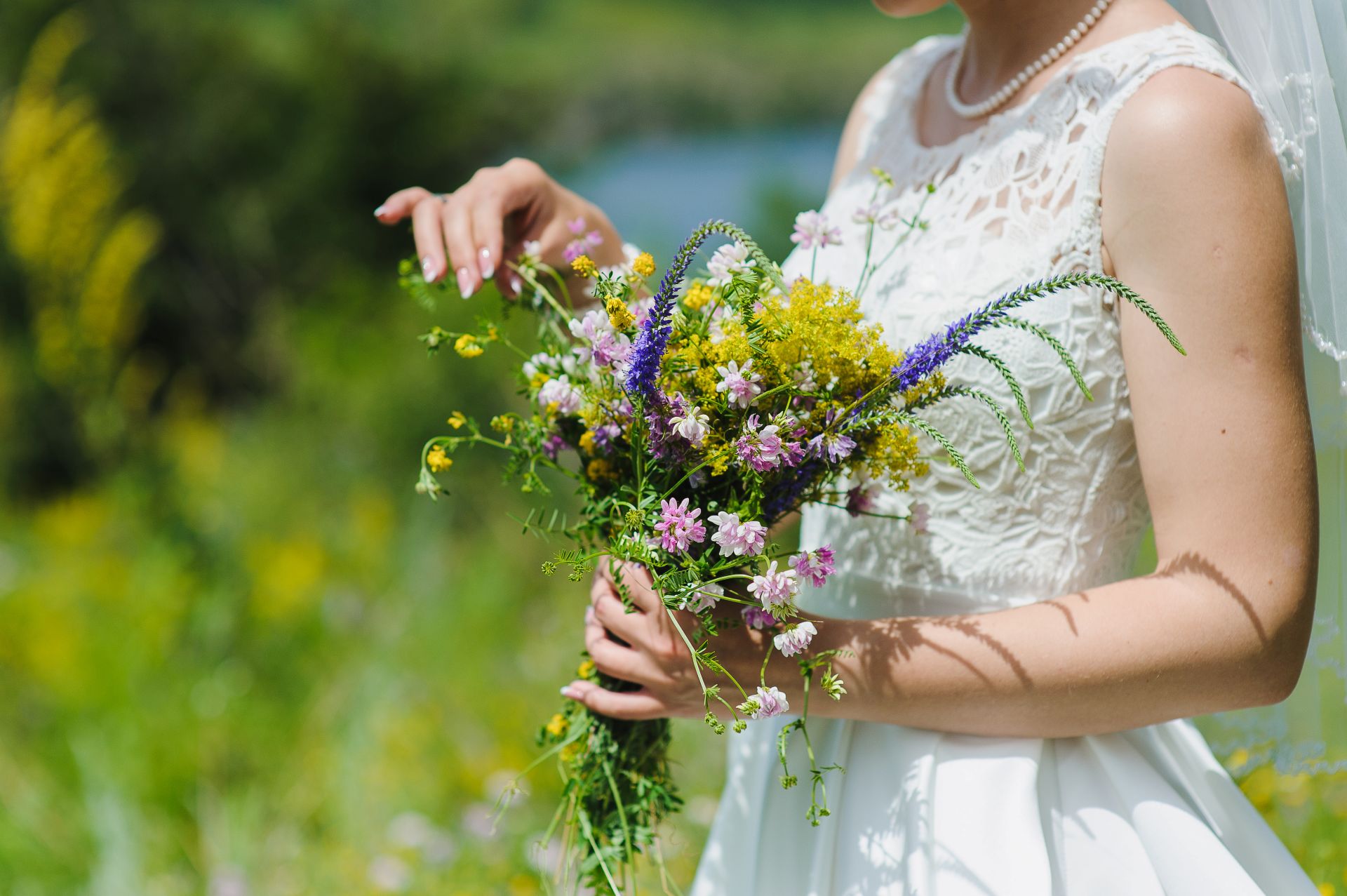 Braut in weissem Kleid haelt natuerlichen Wildblumenstrauss bei freier Trauung in NRW